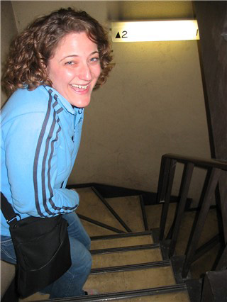 woman standing at the top of a steep dark staircase