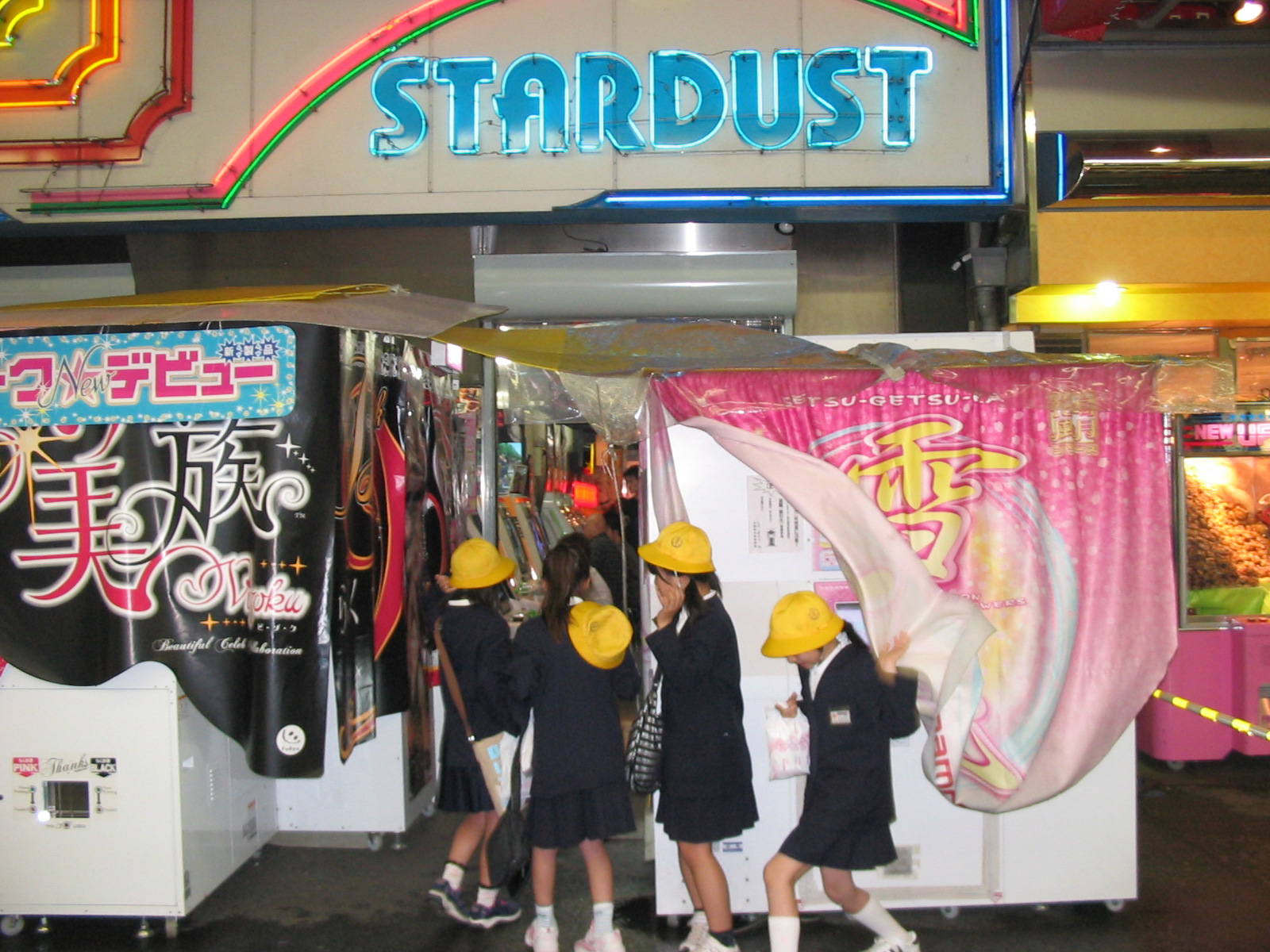 girls come out from under a curtain in front of a blue neon sign that says 'stardust'
