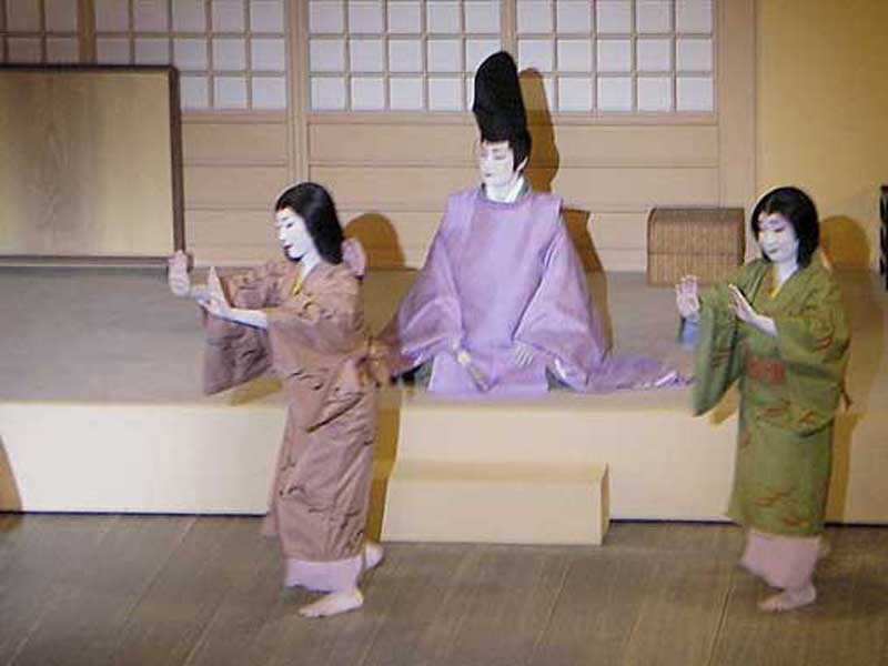 on stage, two women dancing with one man looking on