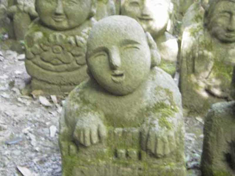 small stone statue surrounded by many statues
