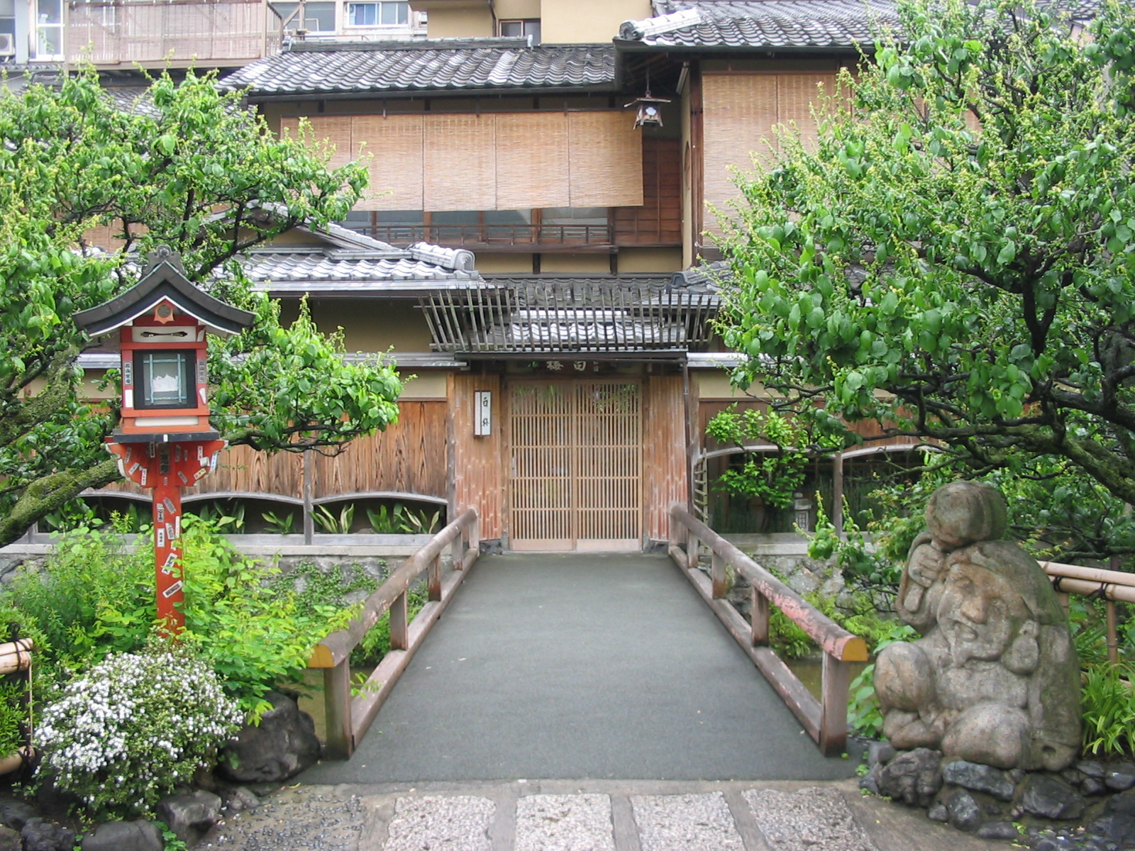 entrance to teahouse with small stone statue and orange mailbox on either side of the sidewalk