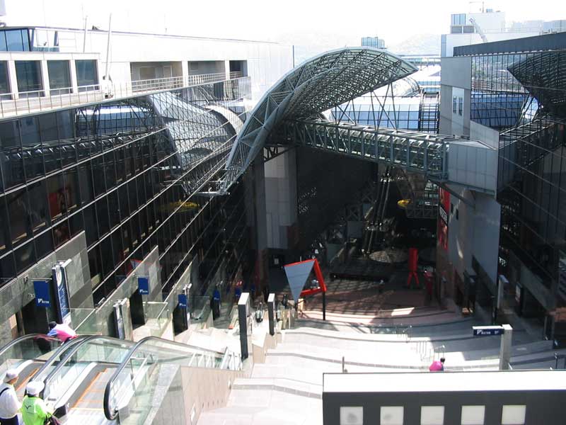 entrance to train station with stairs, escaltor, and glass ceiling