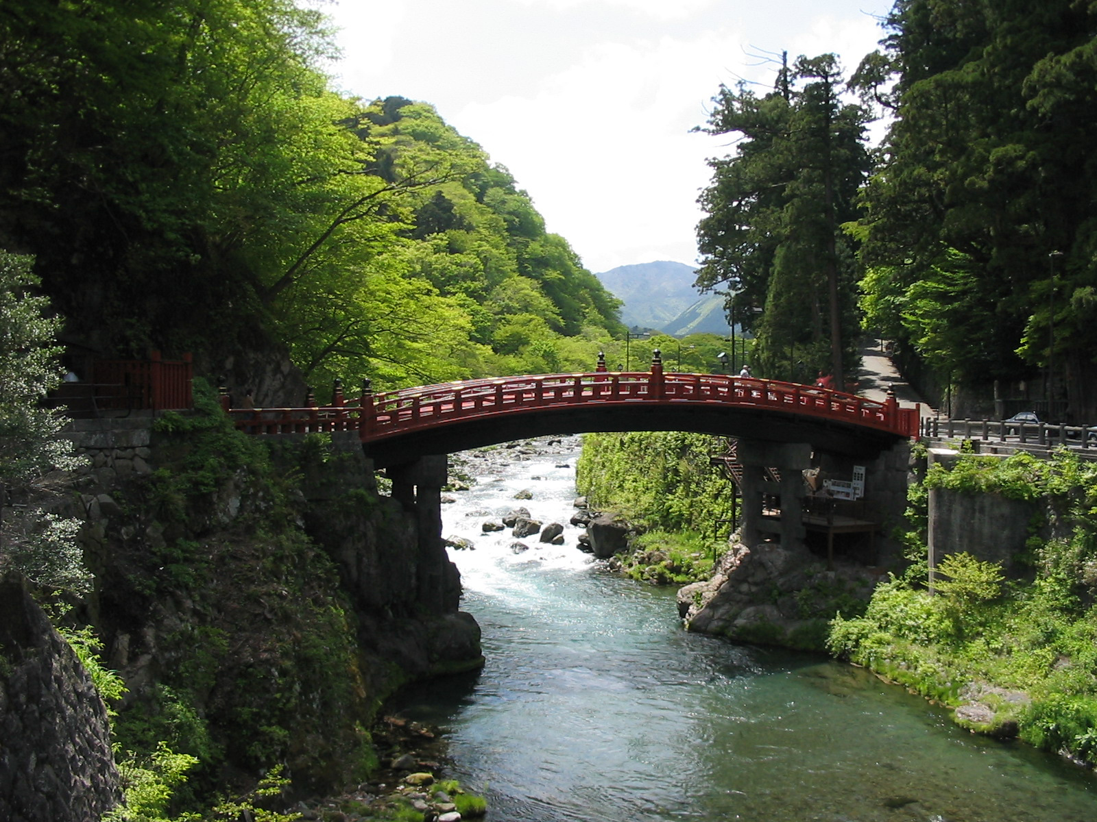 red bridge over a river surrounded by trees