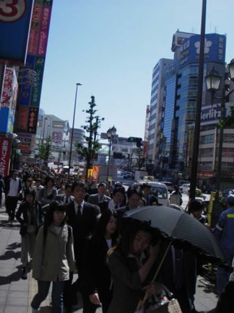 crowd of people walking down the street in the morning