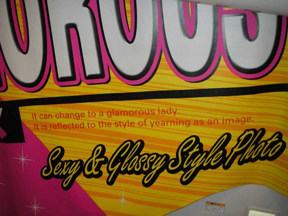 pink and yellow text on the side of a photo booth that says 'it can change to a glamorous lady. It is reflected to the style of yearning as an image.'